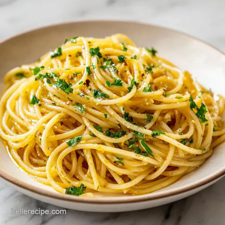 A twirl of golden spaghetti catches the light on a white plate, accented by vibrant green parsley and fiery red chili flakes.