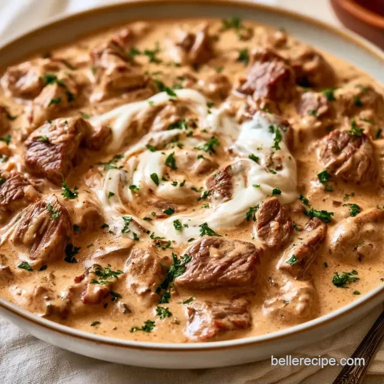 A wide ceramic bowl filled with creamy beef and mushrooms, topped with a sprinkle of bright green chopped parsley.