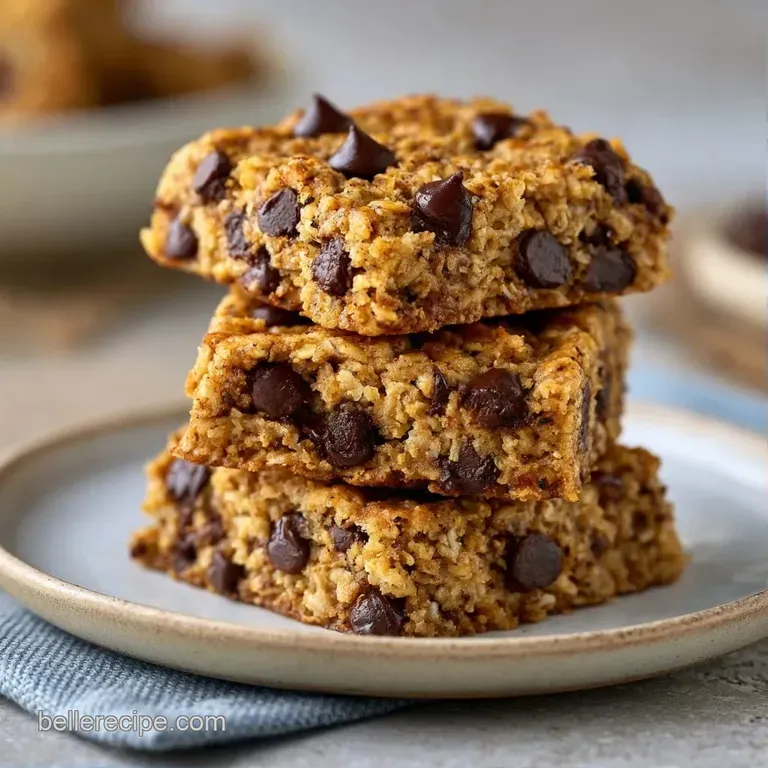 A neat stack of honey-gold oat bars with glistening chocolate chips, placed on a linen napkin by a glass of milk