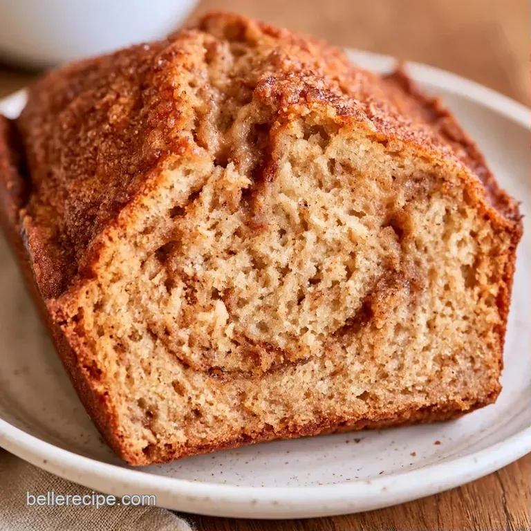 A thick slice of golden-brown spiced loaf topped with a pat of melting butter on a minimalist matte grey plate.