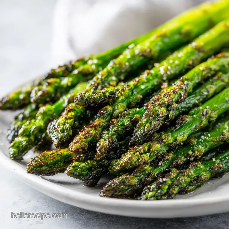 Plated bright green asparagus, roasted to perfection with browned tips, alongside lemon wedges and a sprinkle of sea salt.