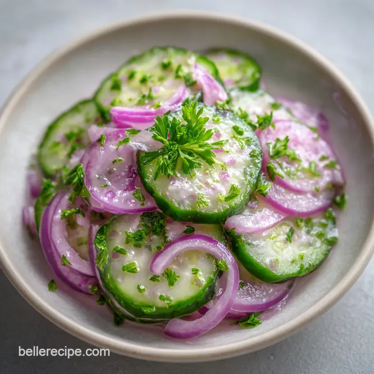 Thinly sliced cucumbers and red onions arranged in a shallow glass bowl with a sprinkle of cracked black pepper.