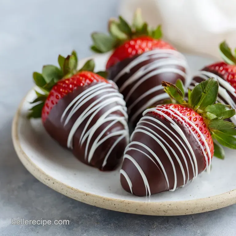 A trio of vibrant red strawberries dipped in dark chocolate, elegantly arranged on a white plate with cocoa powder.