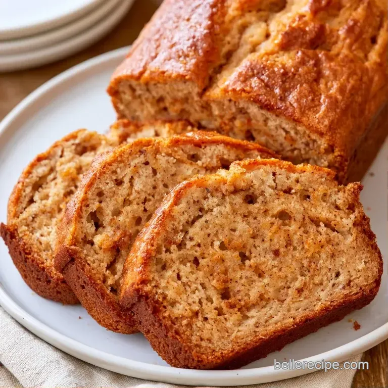 Thick slice of warm, golden-brown cake topped with melting butter on a clean, minimal white ceramic plate.