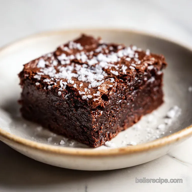 Glossy, dark brownie square on a white plate, topped with a dollop of creamy Greek yogurt and vibrant fresh raspberries. E...
