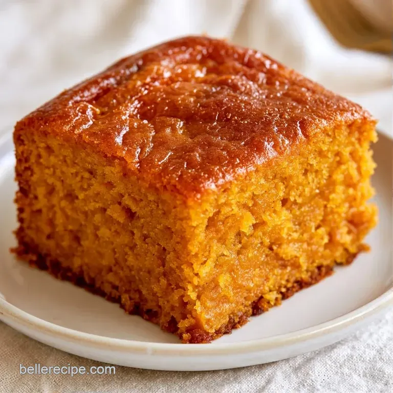 A slice of moist orange cake topped with golden crumbs, paired with a dollop of whipped cream on a white ceramic plate.