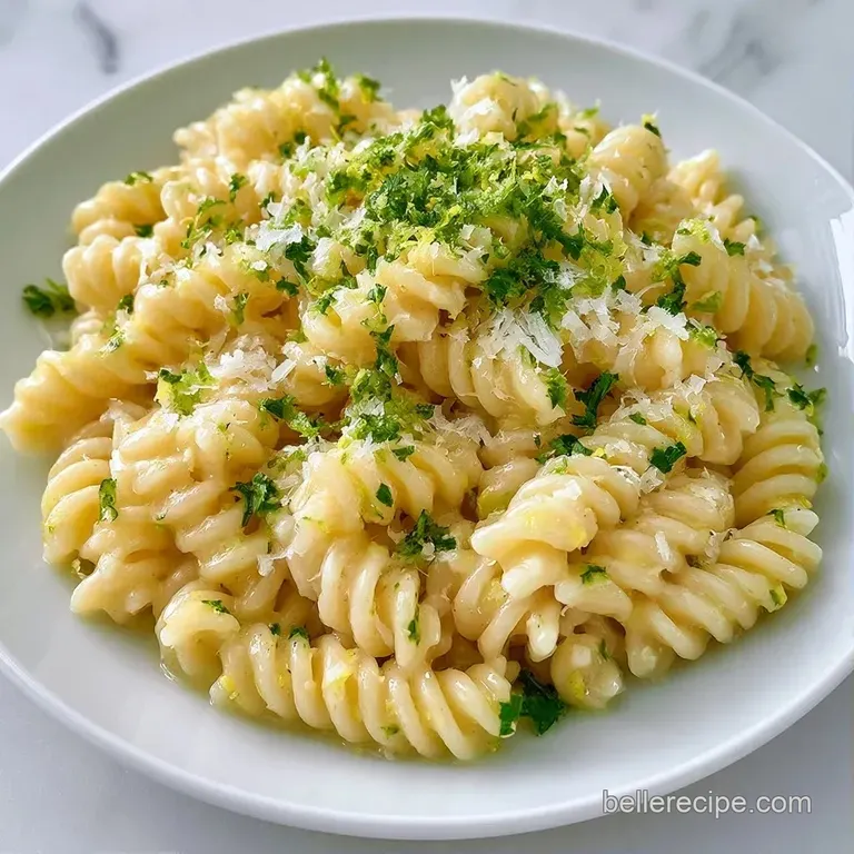 Tossed pasta in a white bowl topped with lemon zest and fresh parsley, set against a clean, bright marble background.