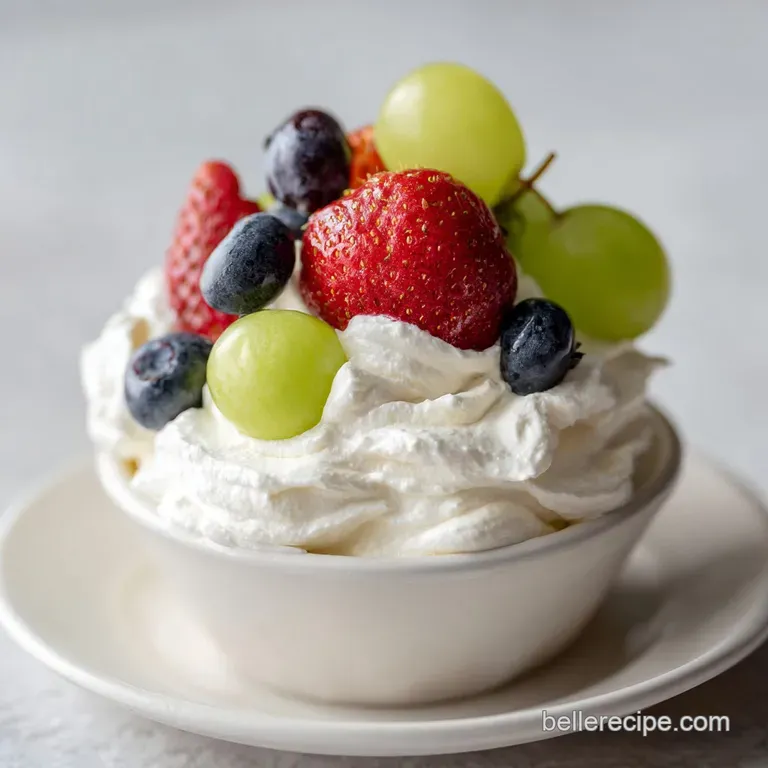 A generous scoop of airy marshmallow dip presented with colorful fresh fruit on a dark slate.