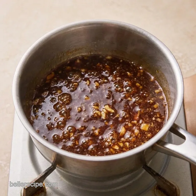 Thick, glossy brown oyster sauce in a small saucepan.