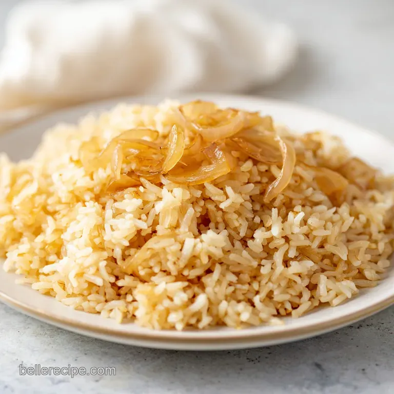A neat dome of fluffy yellow rice topped with fresh parsley and a lemon slice on a polished white plate.